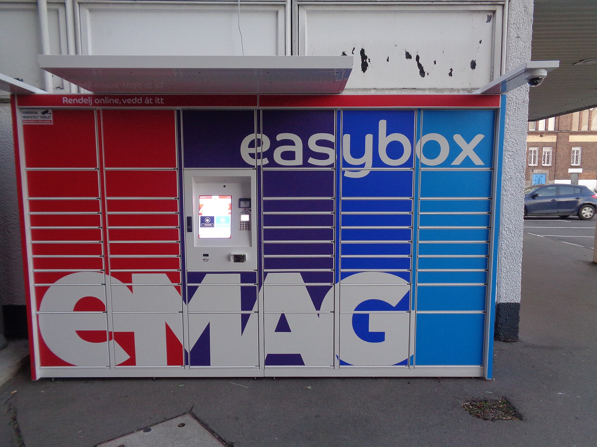 Un locker easybox colorat, în roșu, albastru și bleu, pe o stradă din Budapesta